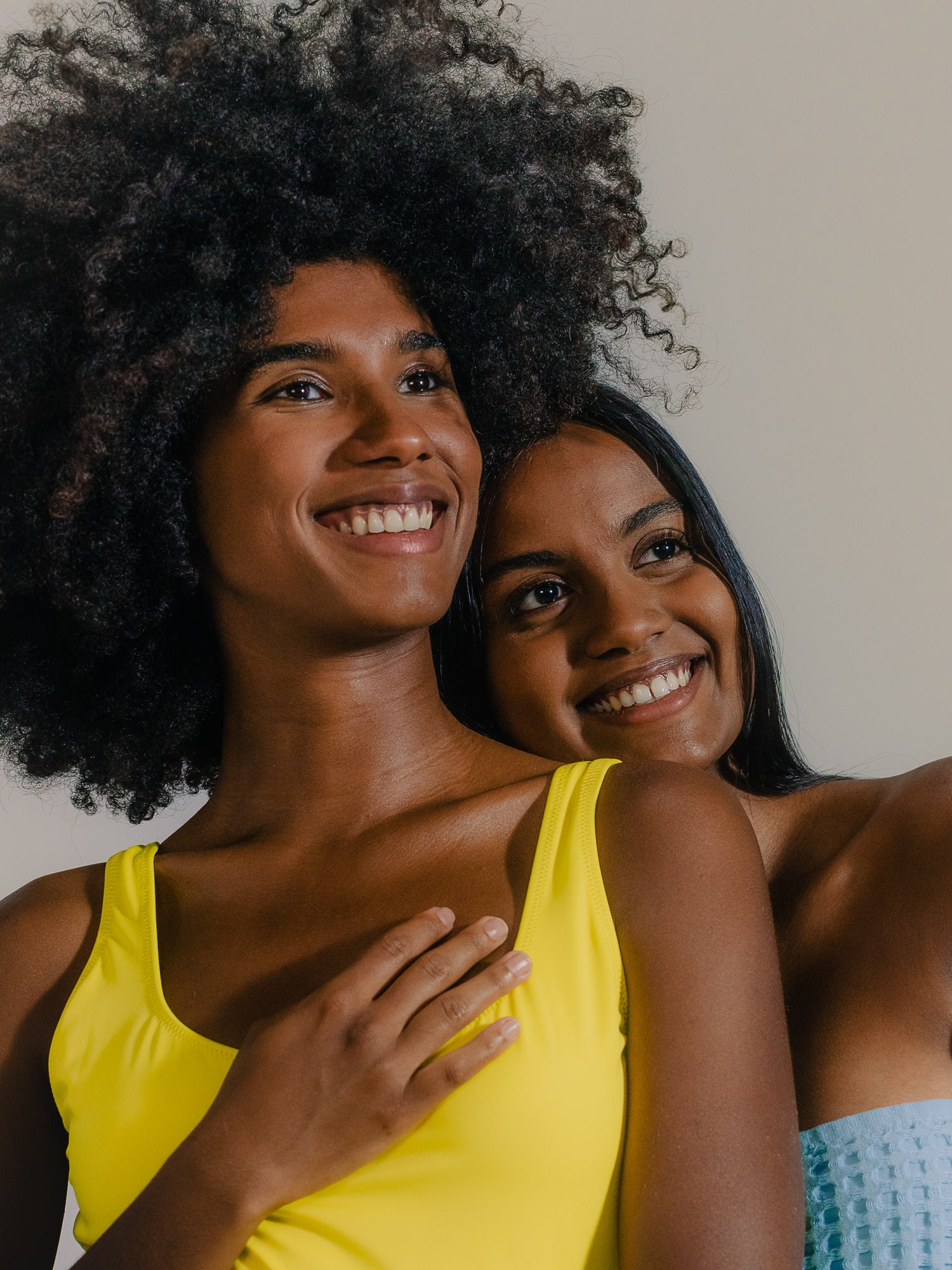 Two women smiling and embracing with a warm and joyful expression.